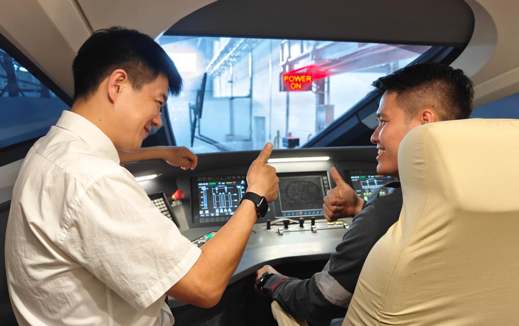 8月25日，在印度尼西亞萬隆的雅萬高鐵德卡魯爾動車所內，中國師傅穆振（左）在向印尼火車司機塞蒂亞萬講解動車組出庫前的上電作業。