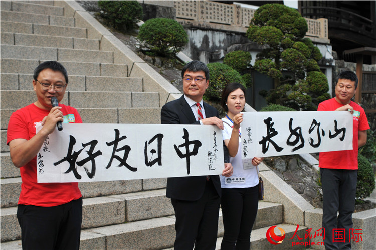 東京中國文化中心主任羅玉泉展示其為本次活動書寫的題詞“中日友好，山高水長”。人民網(wǎng) 蔣曉辰攝