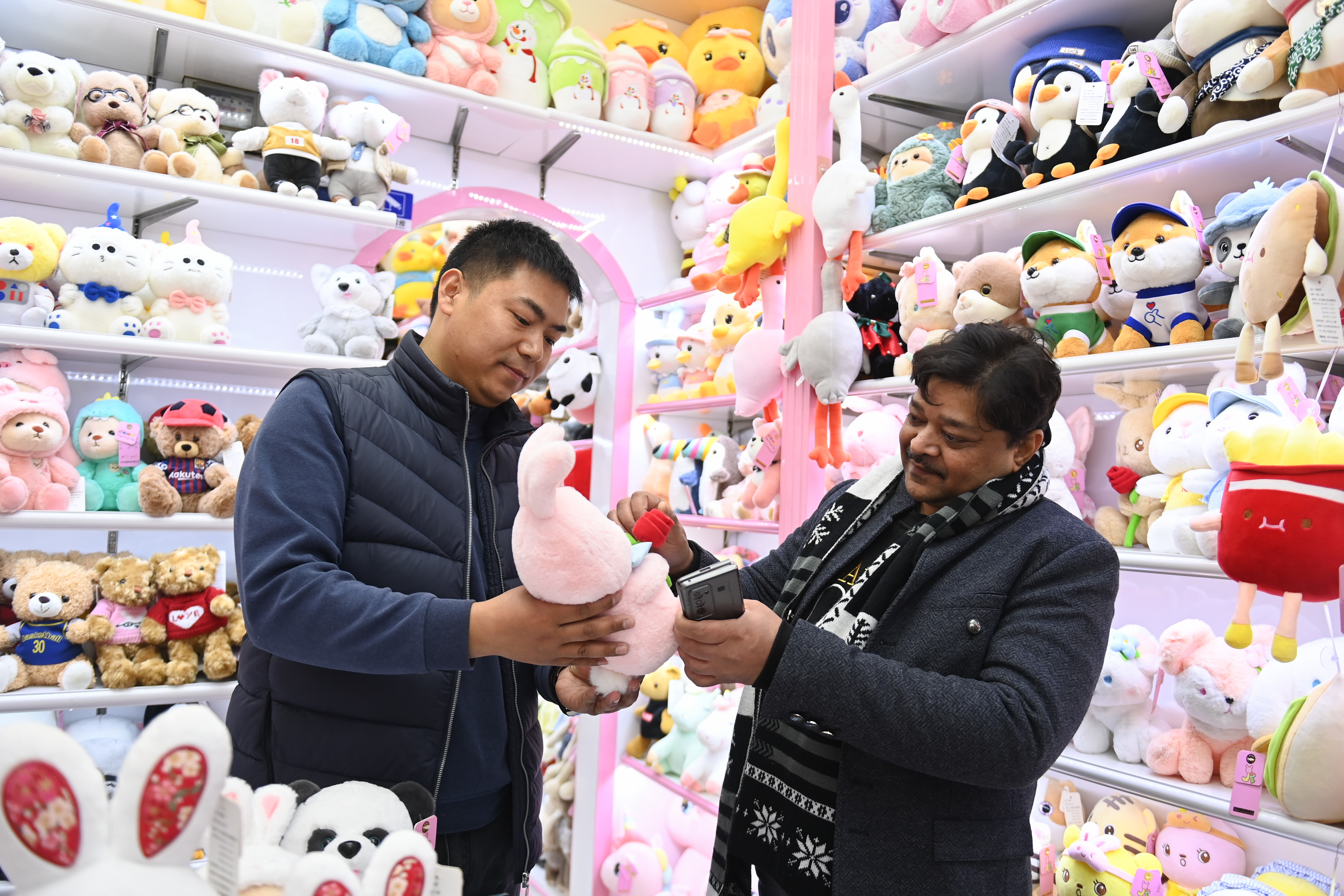 2023年2月2日，來自印度的客商（右）在義烏國際商貿(mào)城的一家玩具店鋪內(nèi)選購。