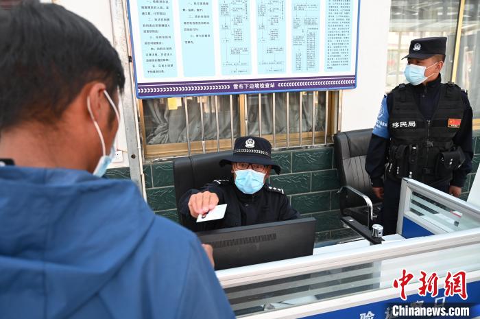 圖為移民管理警察登記完身份信息后將證件歸還給行人?！≮w朗 攝