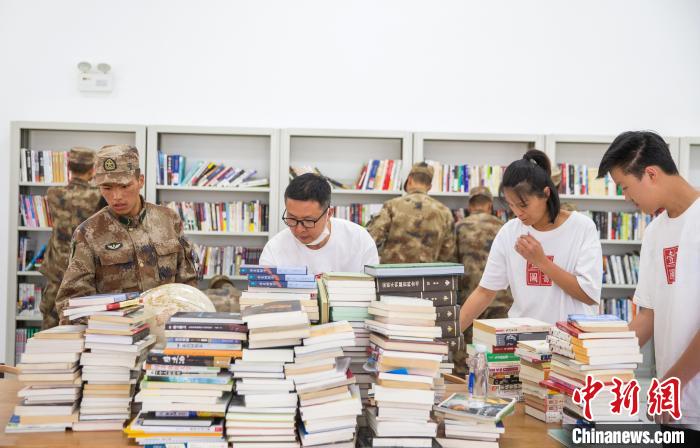 圖為志愿者們和邊防戰(zhàn)士整理圖書?！詵| 攝